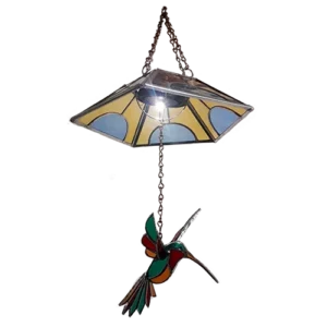 Lámpara de colibrí encendida, con luz bajo la pantalla de vidrio y celda solar en la parte superior.