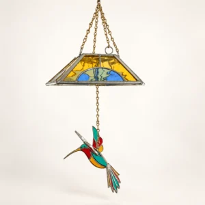 Lámpara colgante con pantalla de vidrio amarillo y azul y figura de colibrí de colores.